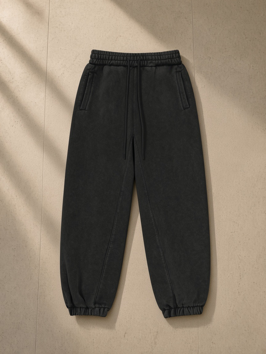 Fleeced Jogger Sweatpants in Black, laid flat on pale limestone