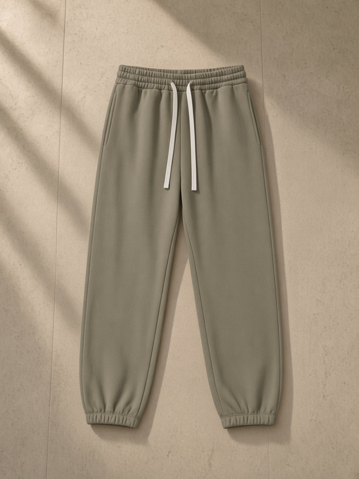 Essential Fleece Sweatpants in Carbon Gray, laid flat on pale limestone, front.