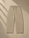Unisex mineral wash barrel leg pants in Khaki, laid flat on pale limestone