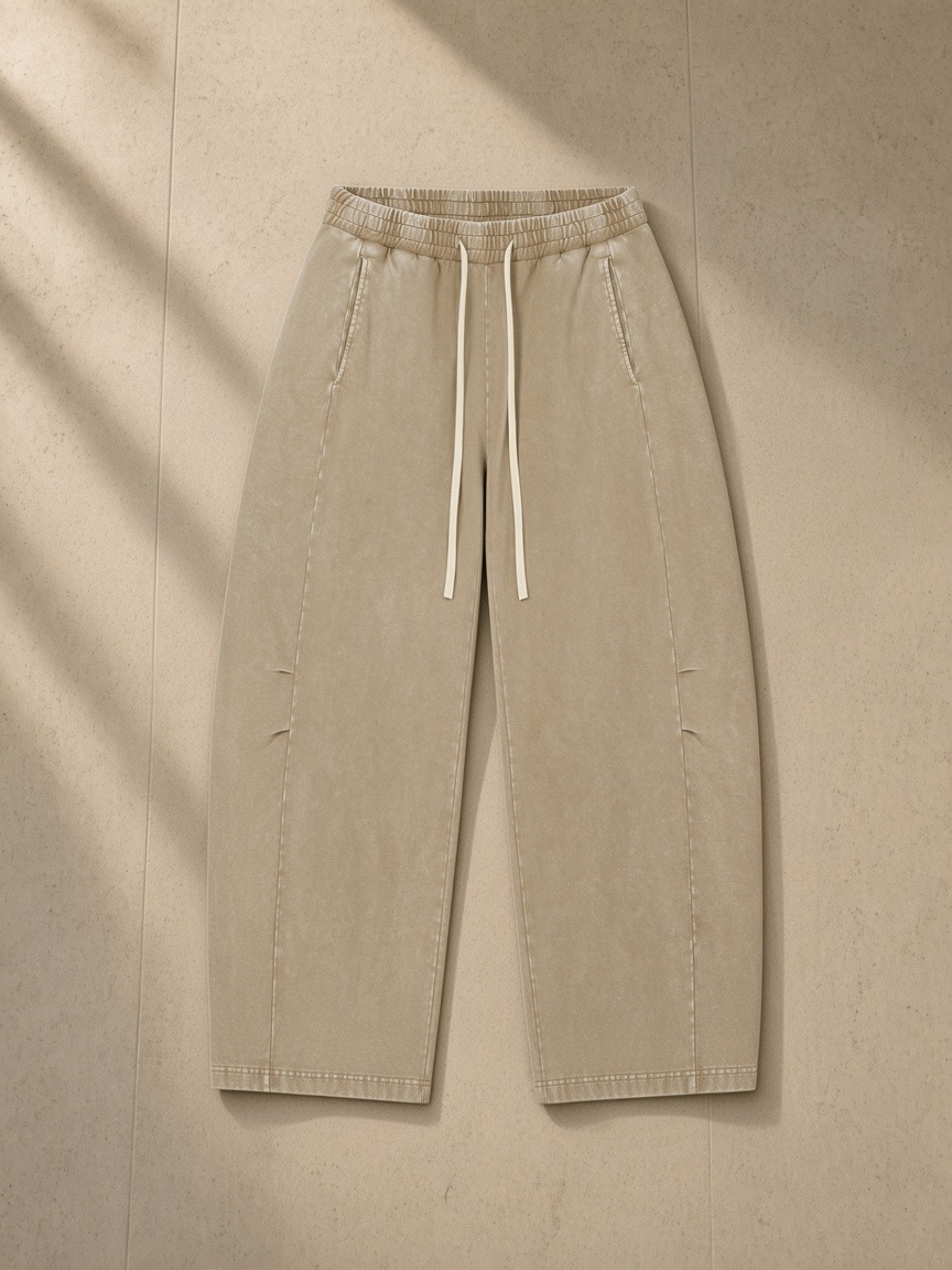 Unisex mineral wash barrel leg pants in Khaki, laid flat on pale limestone