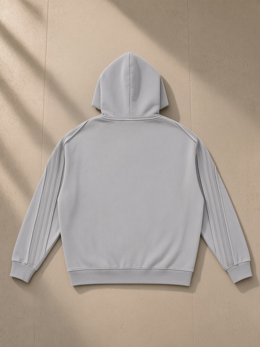 Unisex snow washed tape raw edge zip hoodie in Light Gray, laid flat on pale limestone, back view