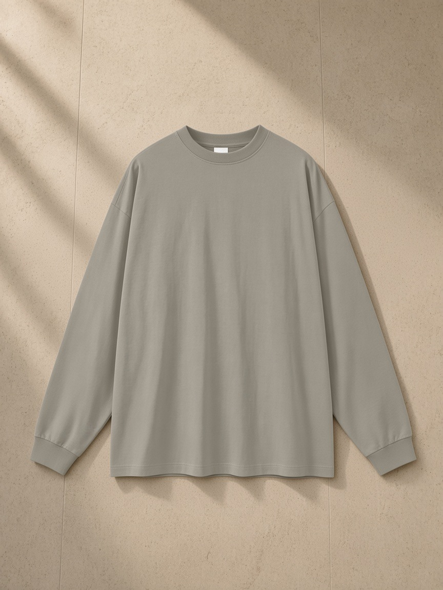 Oversized Long Sleeve T-Shirt in Gray Camel, laid flat on pale limestone