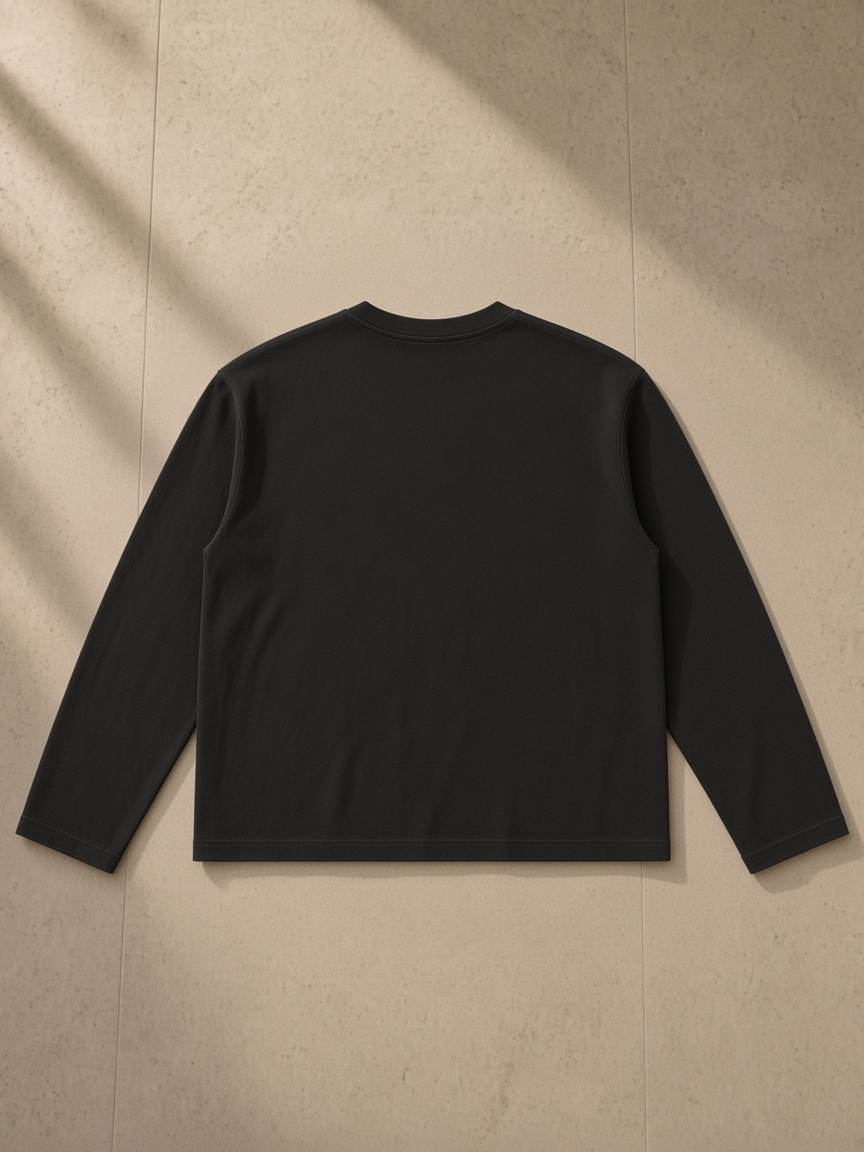 Vintage Wash Long Sleeve Boxy T-Shirt in Black, laid flat on pale limestone, back.