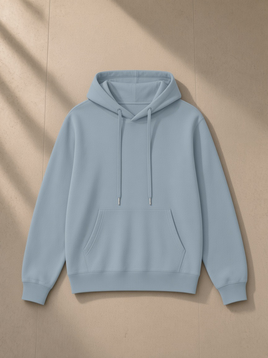 Unisex classic cotton hoodie in Haze Blue, laid flat on pale limestone