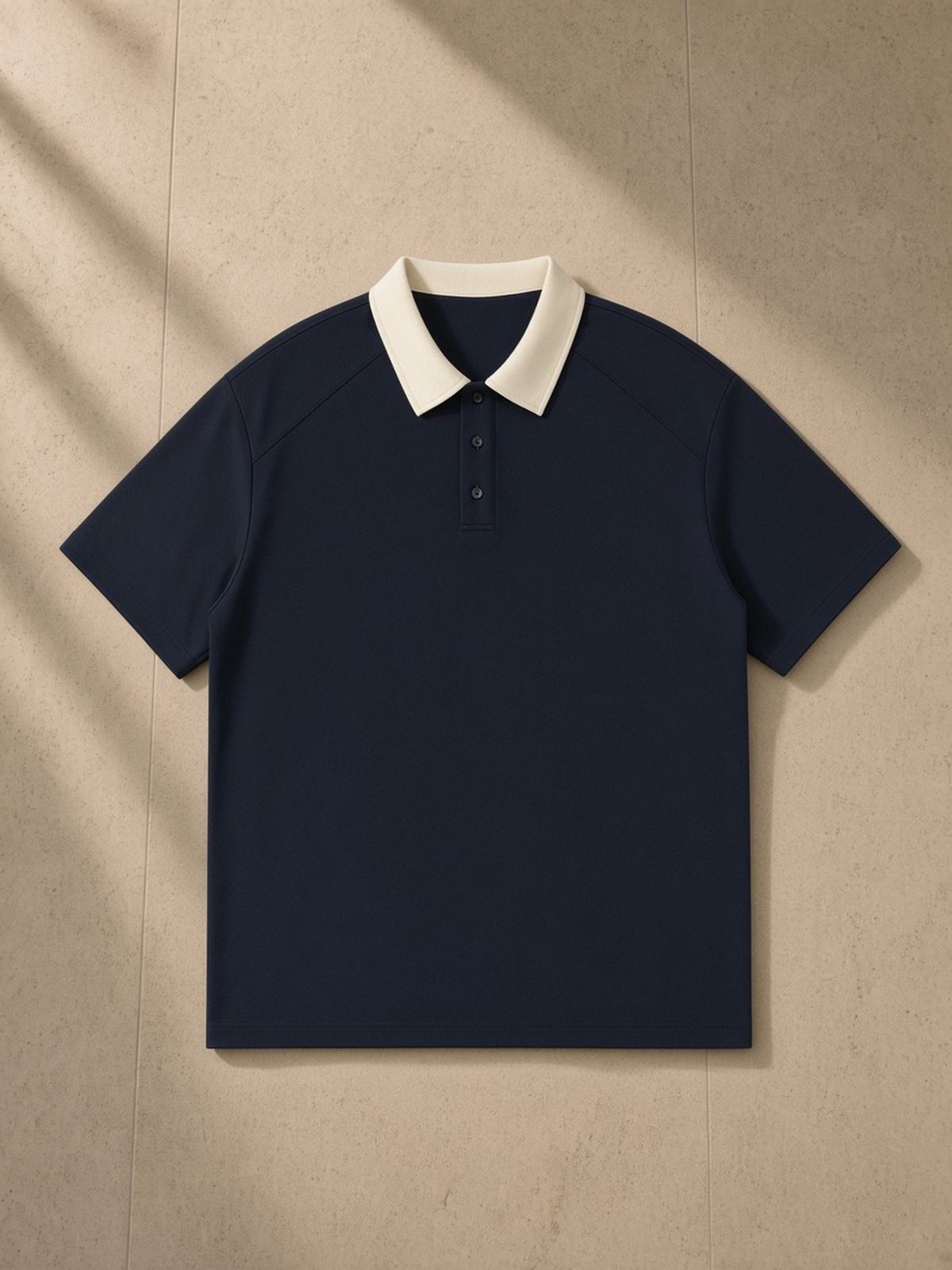 Contrast Collar Raglan Polo Shirt in Navy Blue, laid flat on pale limestone, front.
