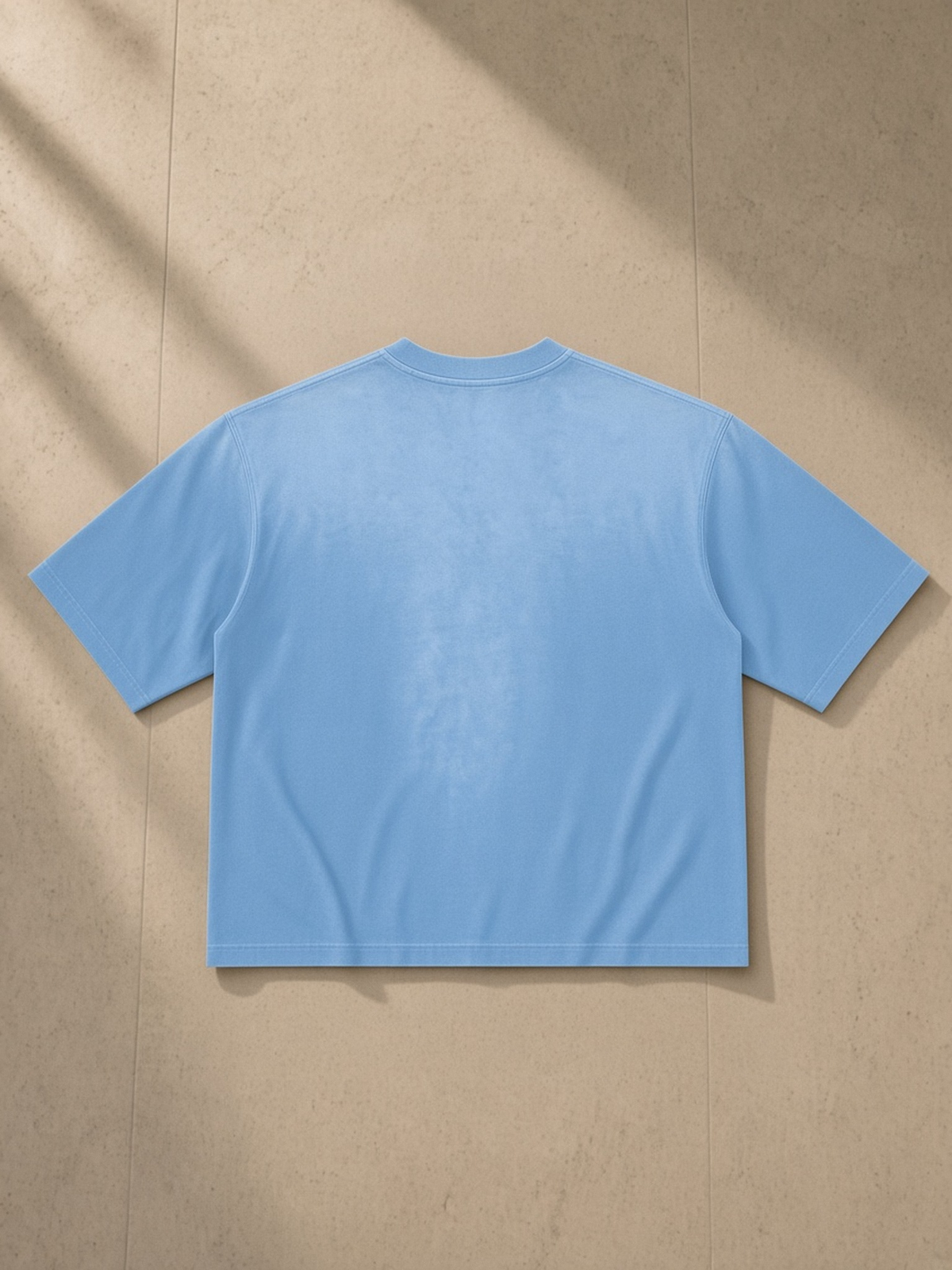 Vintage Wash Sunfade Boxy T-Shirt in Sky Blue, laid flat on pale limestone, back view