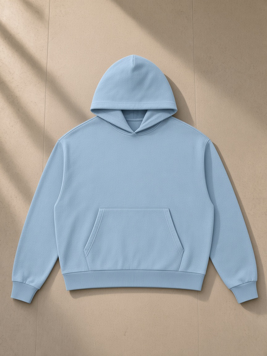 Mineral Wash Boxy Hoodie in Haze Blue, laid flat on pale limestone