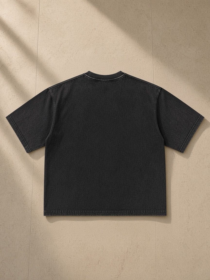 Men's Heavyweight Mineral Wash Boxy T-Shirt in Black, laid flat on pale limestone, back view