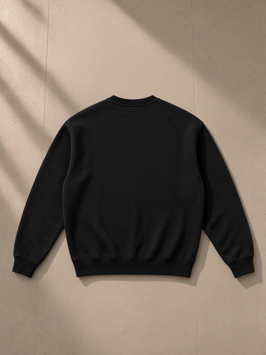 Fleeced sweatshirt in Black, laid flat on pale limestone, back view