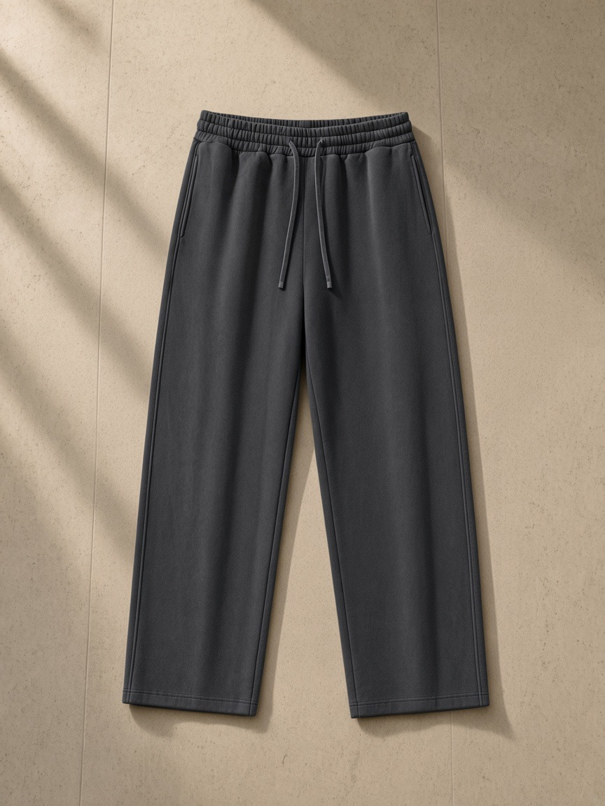 Snow Washed Raw Edge Sweatpants in Dark Gray, laid flat on pale limestone