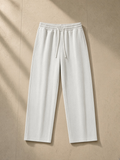 Straight-leg sweatpants in Oat Gray, laid flat on pale limestone