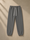 Essential fleece sweatpants in Cement Gray, laid flat on pale limestone