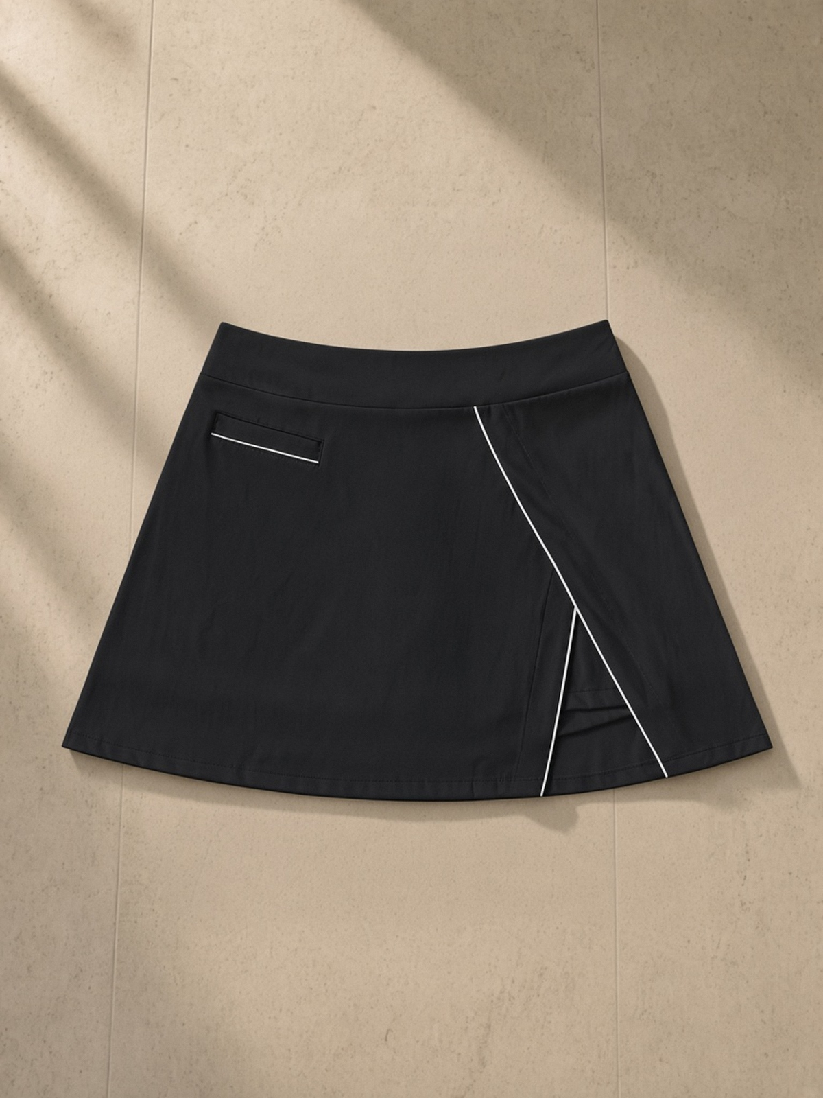 High-Waist Pocketed A-Line Skirt in Black, laid flat on pale limestone, front.