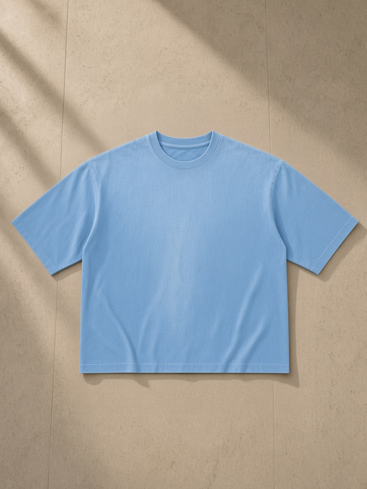 Vintage Wash Sunfade Boxy T-Shirt in Sky Blue, laid flat on pale limestone, front view