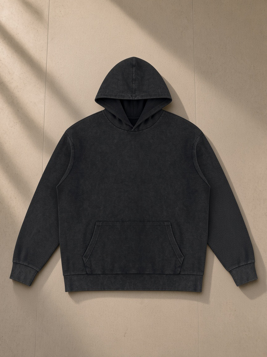 Mineral Wash Oversized Hoodie in Black, laid flat on pale limestone