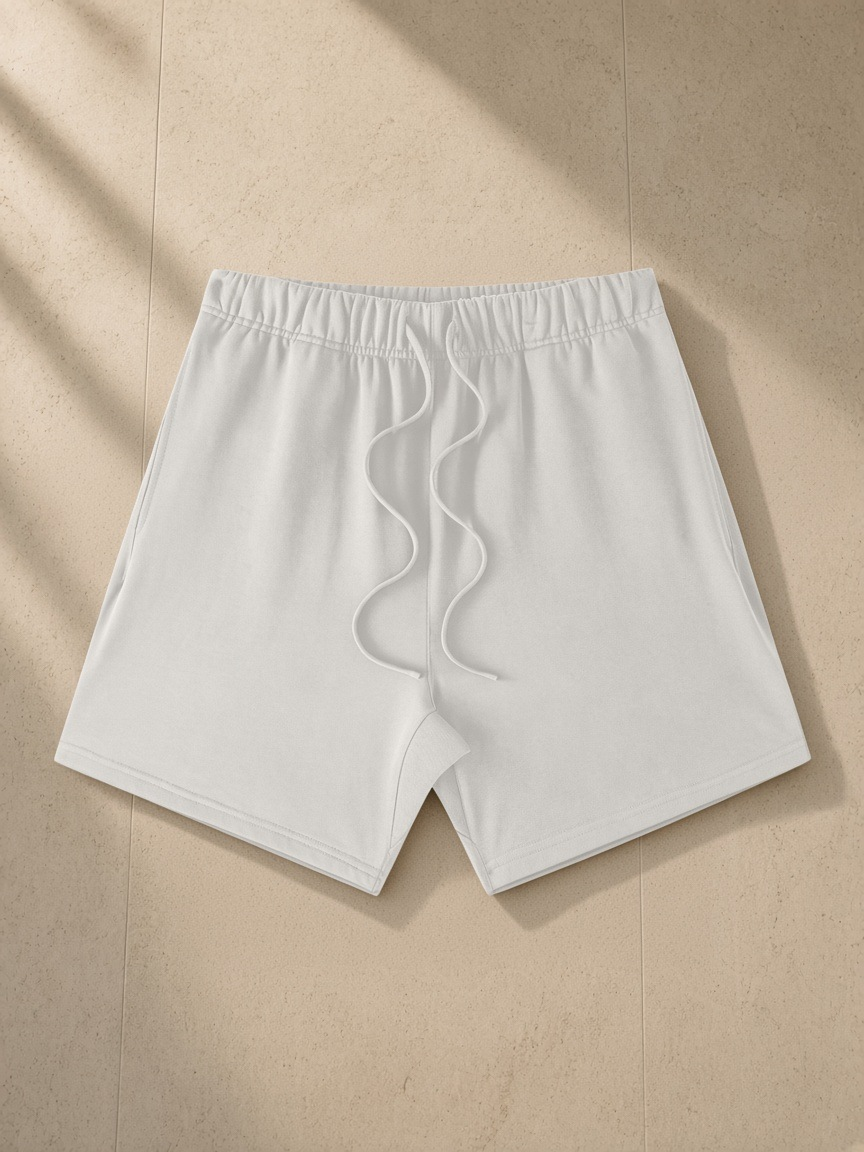 Earth Tone Loose Fit Cotton Shorts in Oat Gray, laid flat on pale limestone
