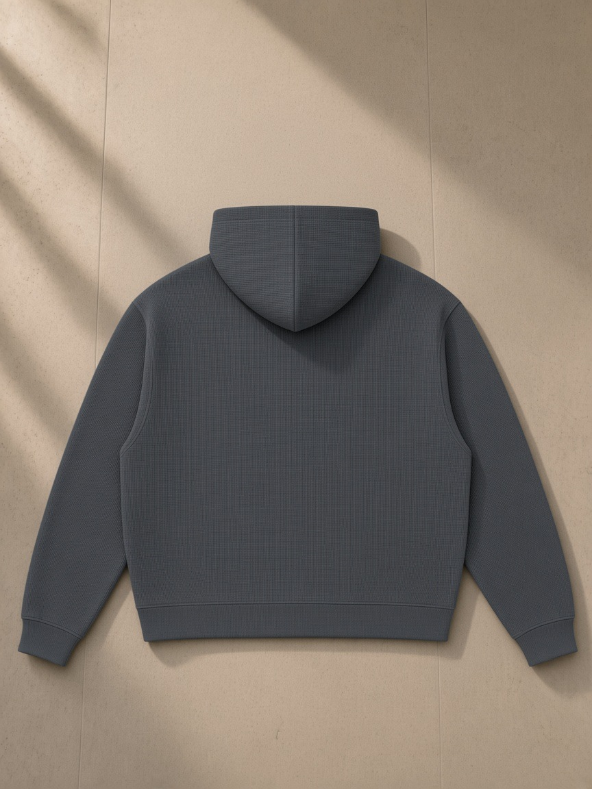 Unisex waffle boxy full zip hoodie in Dark Gray, laid flat on pale limestone, back view