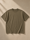Unisex heavyweight drop shoulder cotton t-shirt in Deep Khaki tossed over a bouclé armchair in a Montana ranch lodge at night