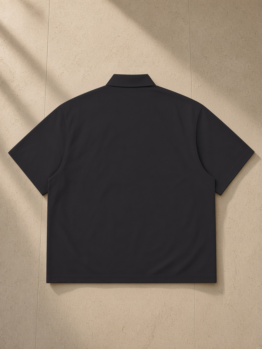 Lightweight Cotton Short Sleeve Shirt in Black, laid flat on pale limestone, back view