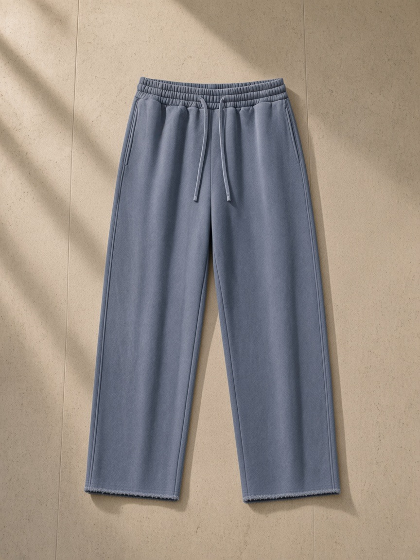 Frayed enzyme washed fleece sweatpants in Blue, laid flat on pale limestone