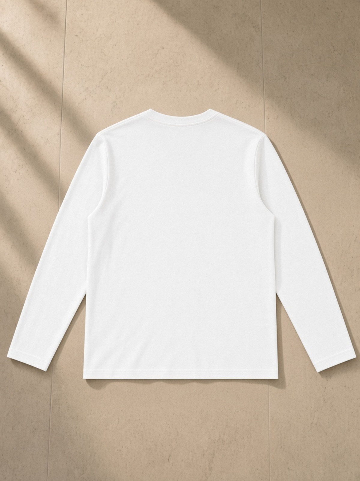 Heavyweight Long Sleeve T-Shirt in White, laid flat on pale limestone, back.