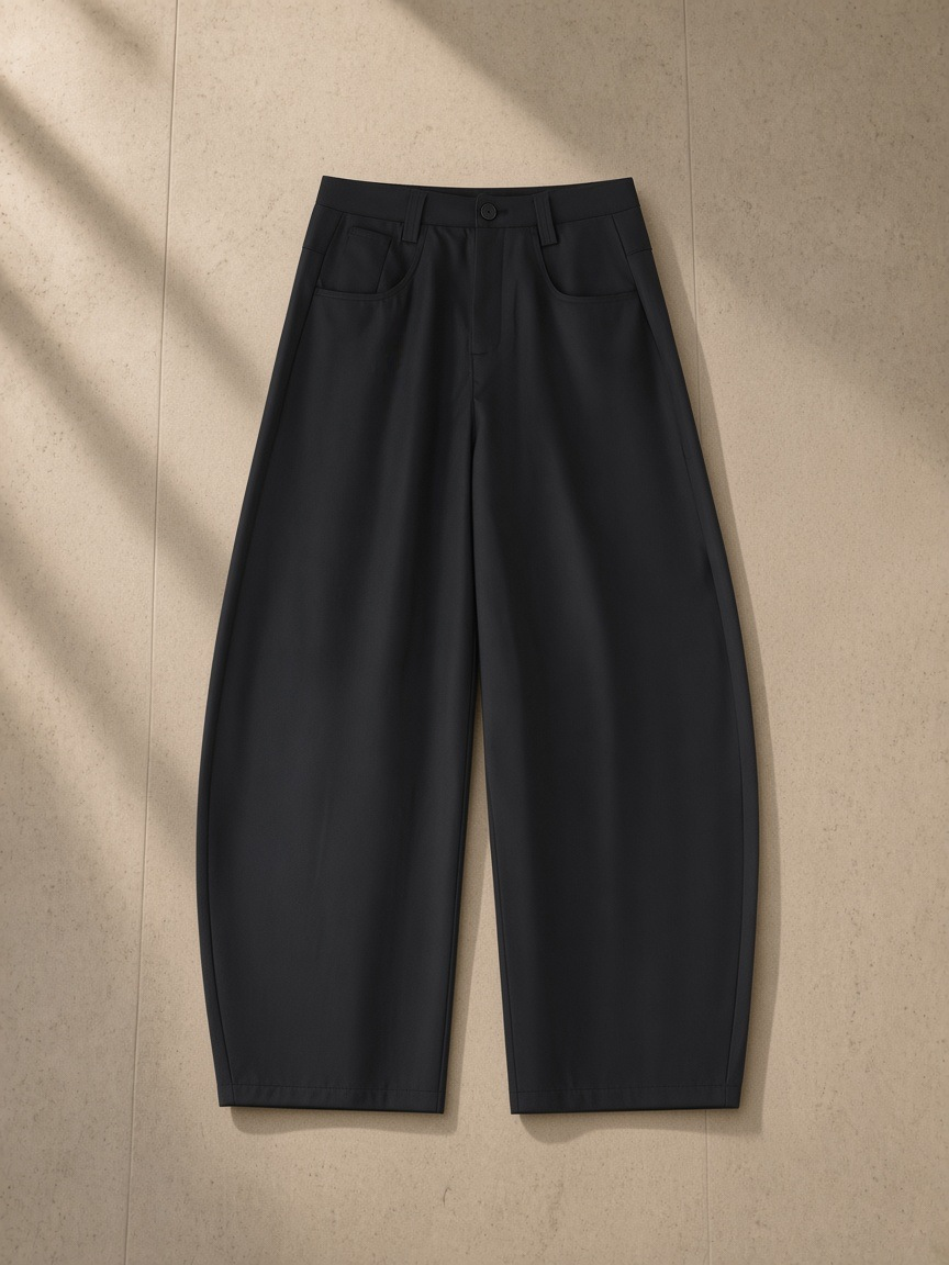 Essential Barrel Dress Pants in Black, laid flat on pale limestone