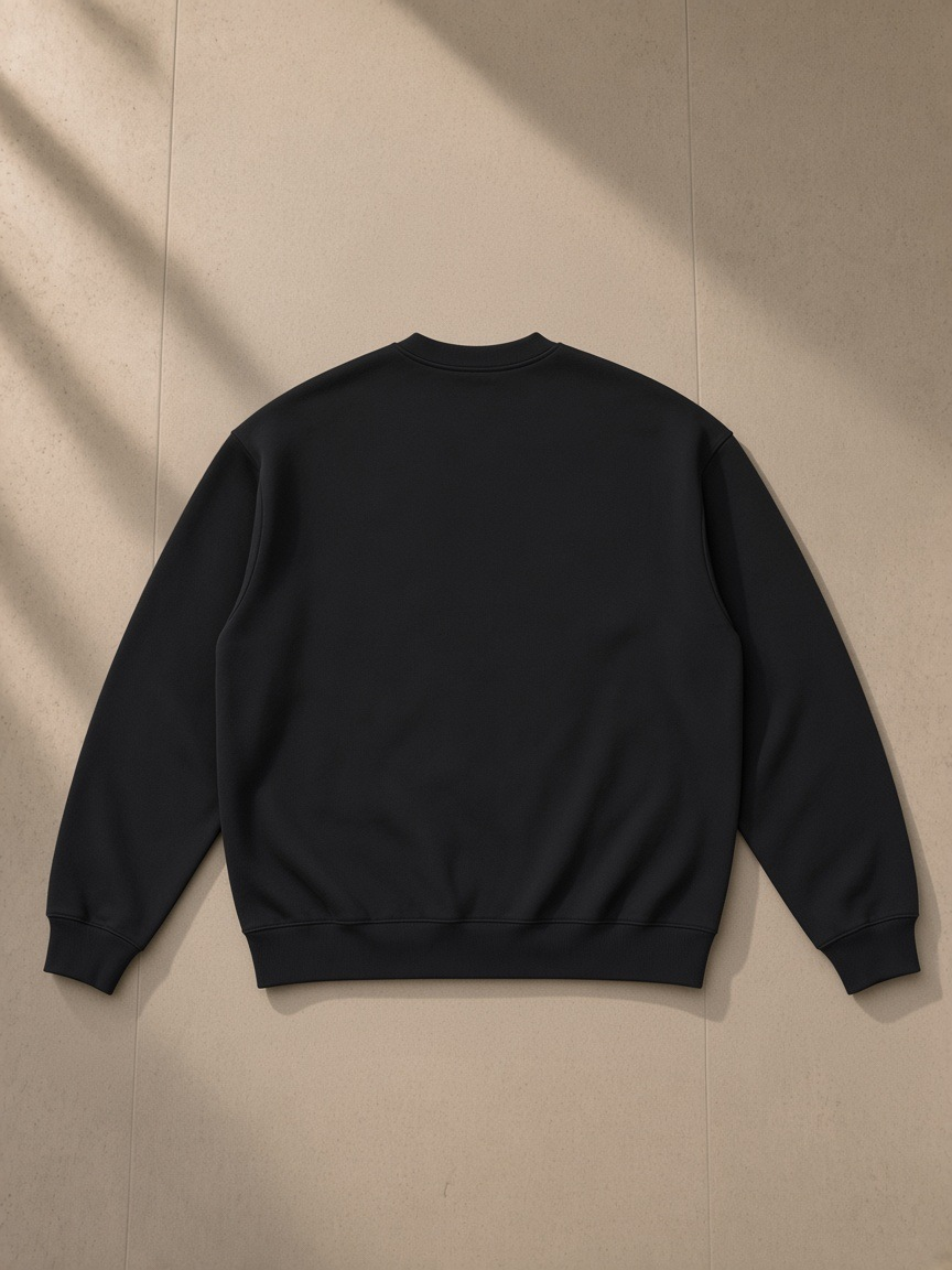 Oversized drop shoulder crewneck sweatshirt in Black, laid flat on pale limestone, back view