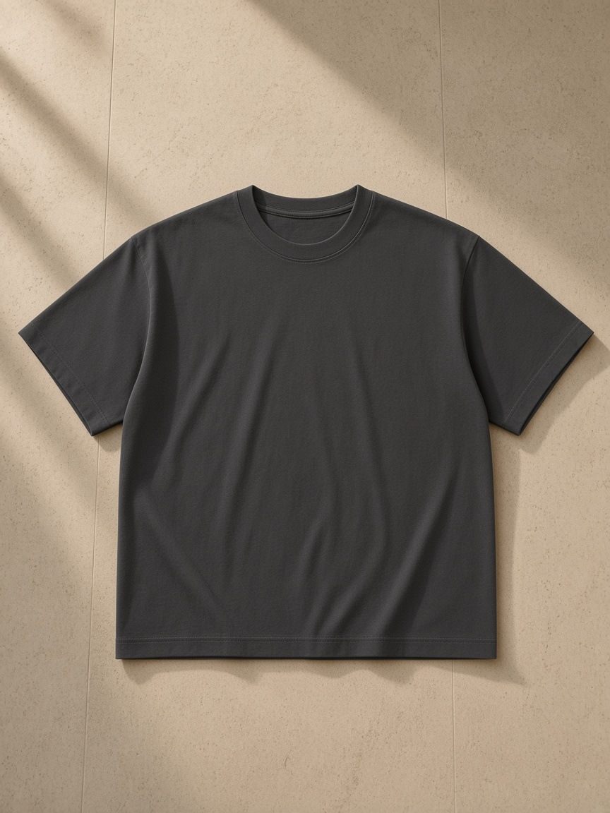 Unisex cotton boxy t-shirt in Dark Gray, laid flat on pale limestone