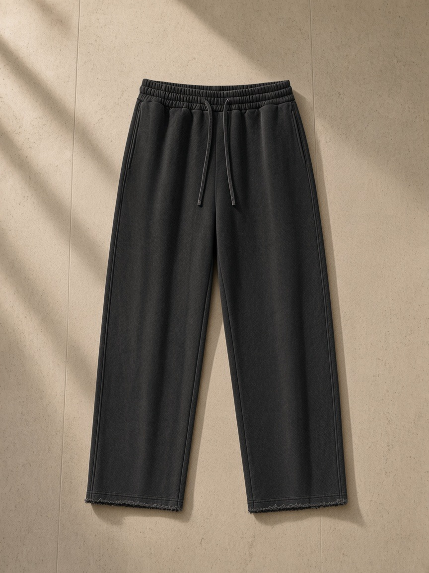 Frayed enzyme washed fleece sweatpants in Black, laid flat on pale limestone