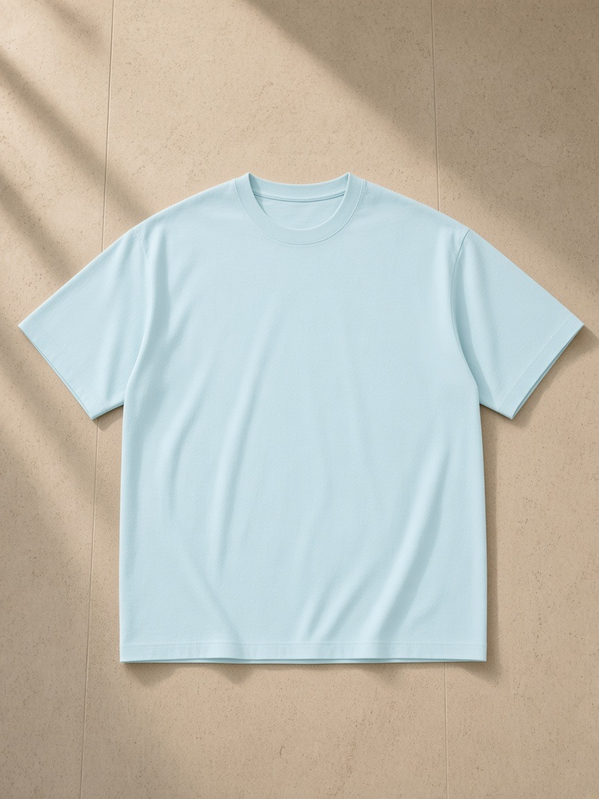 Unisex pure cotton t-shirt in Light Blue, laid flat on pale limestone