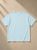 Unisex pure cotton t-shirt in Light Blue, laid flat on pale limestone