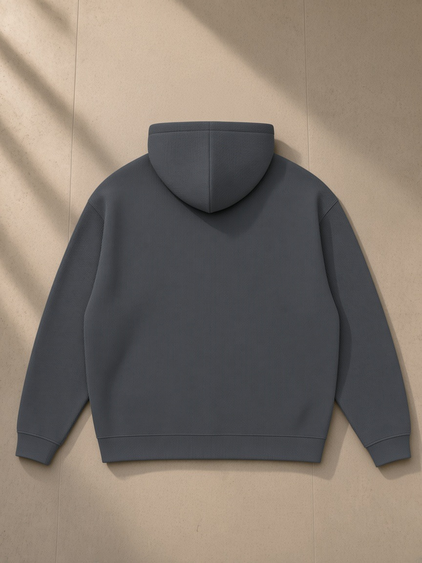 Waffle Hoodie in Dark Gray, laid flat on pale limestone, back view