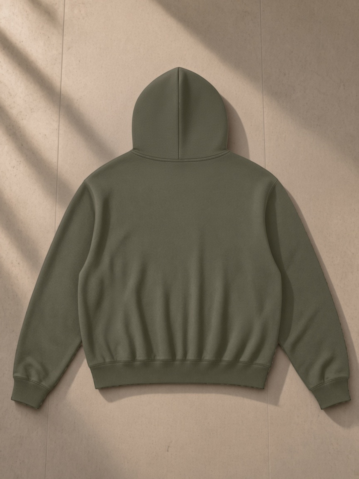Oversized Drop Shoulder Hoodie in Army Green, laid flat on pale limestone, back.