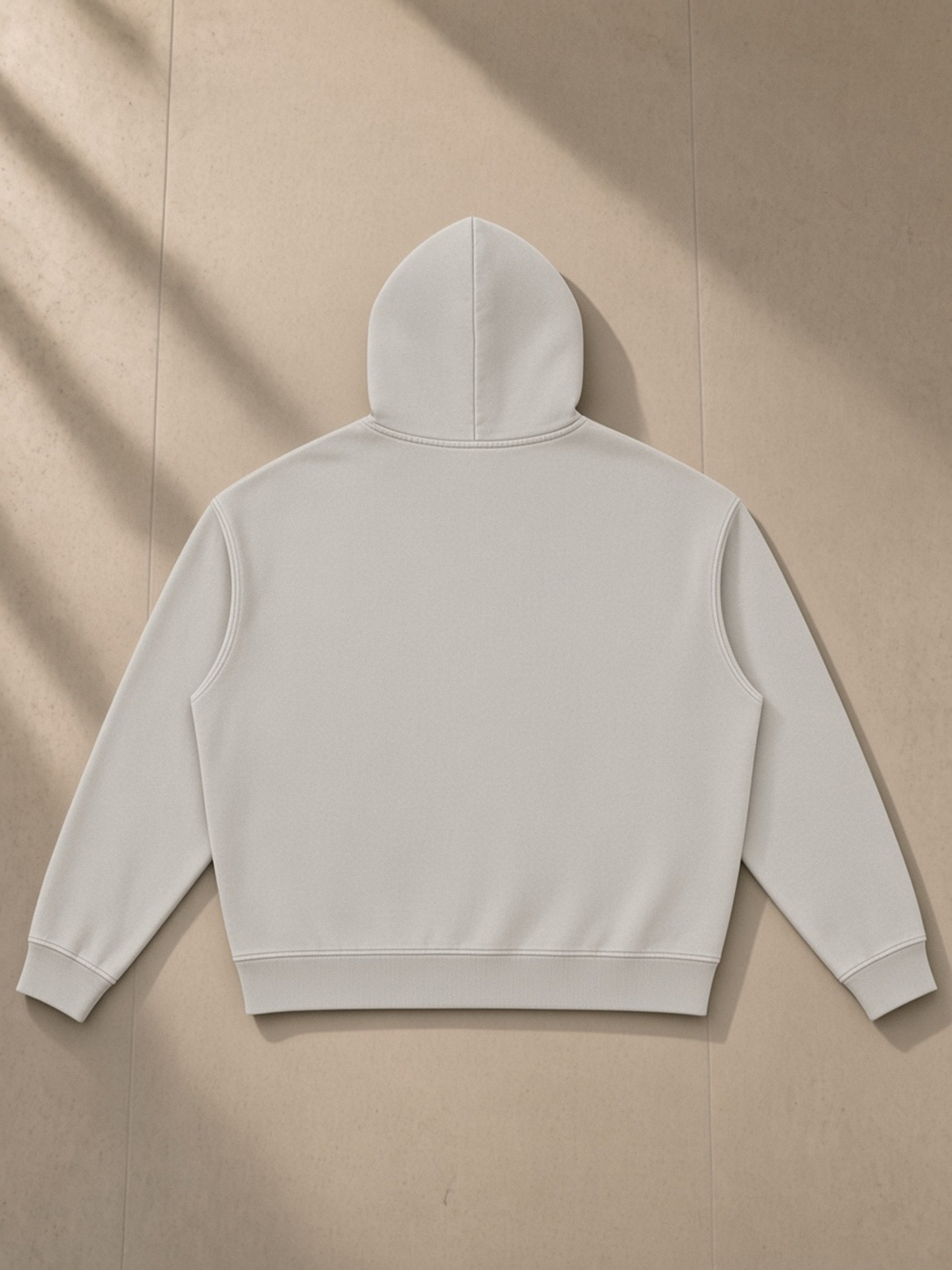 Vintage Wash Boxy Hoodie in Light Gray, laid flat on pale limestone, back.