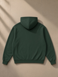 Unisex loose full zip hoodie in Blackish Green, laid flat on pale limestone, back view
