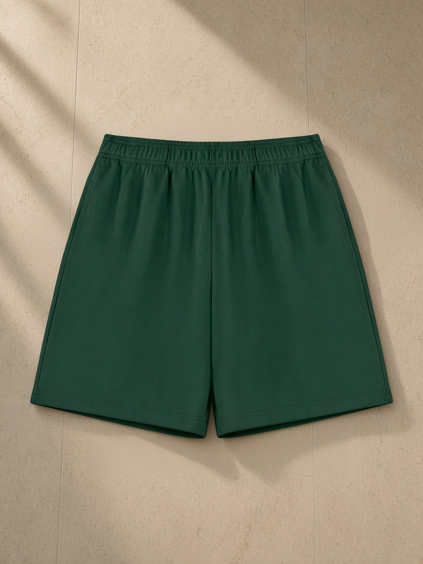 Cotton Shorts in Blackish Green, laid flat on pale limestone
