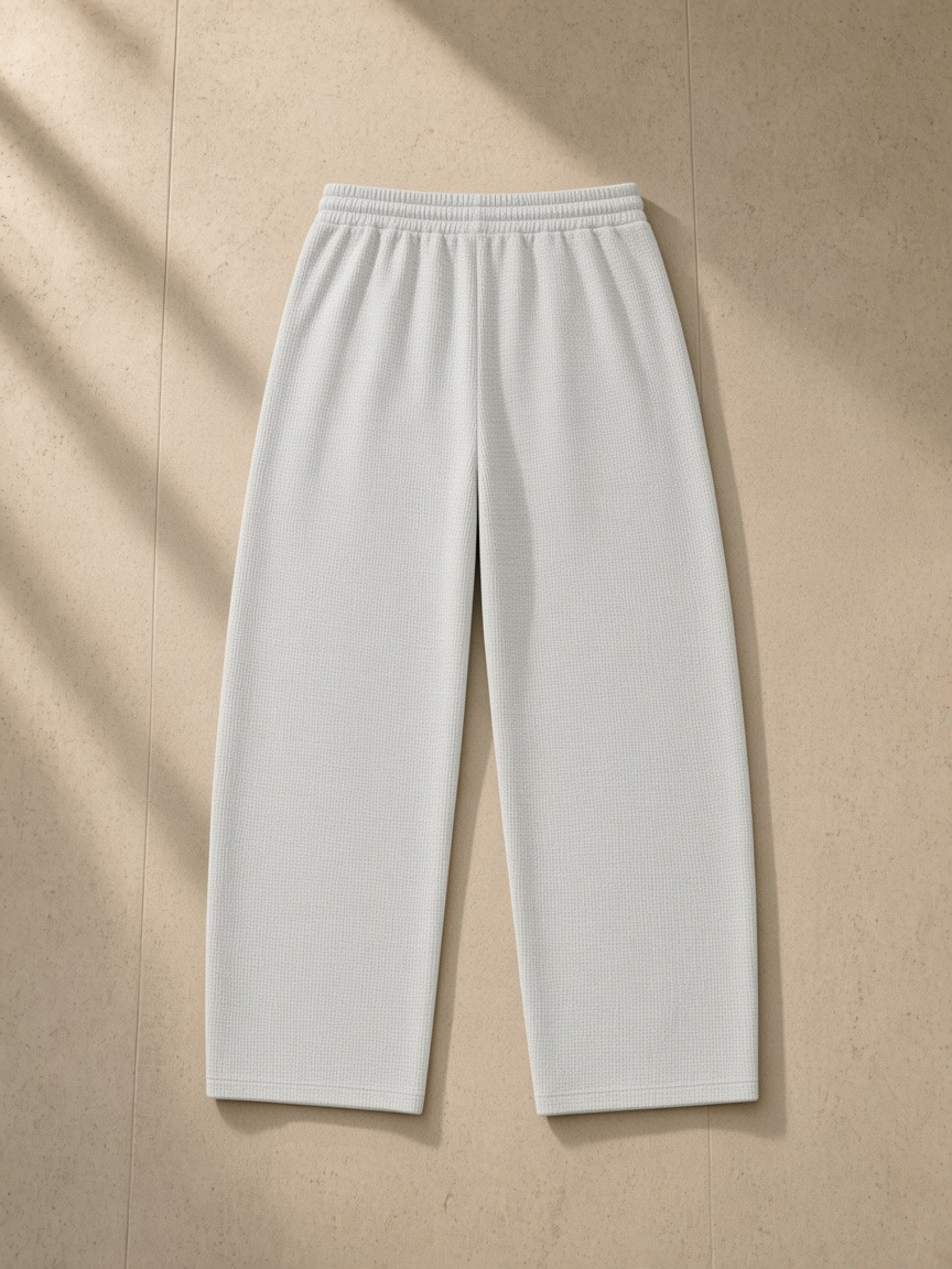 Waffle barrel leg pants in Oat Gray, laid flat on pale limestone, back view