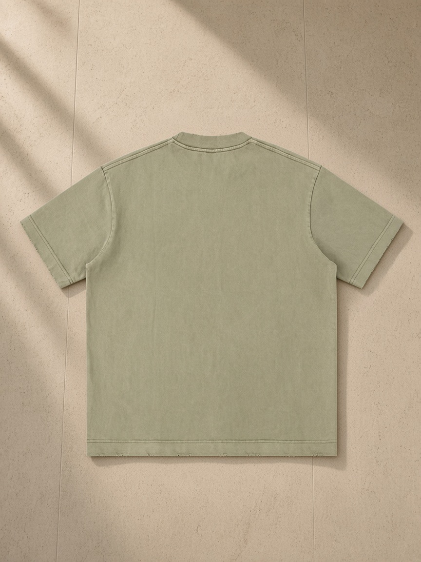 Heavyweight Vintage Washed Frayed T-Shirt in Gray Green, laid flat on pale limestone, back view