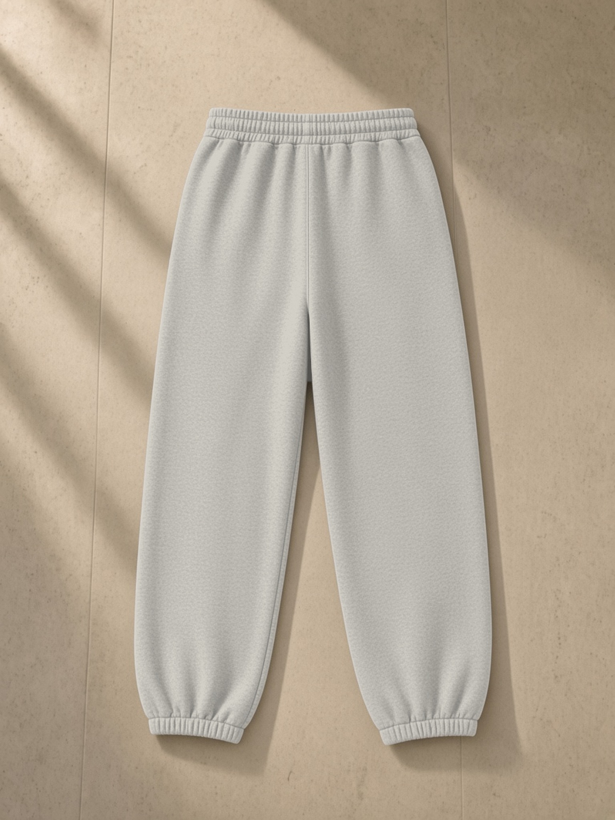 Vintage Washed Fleece Jogger Sweatpants in Light Gray, laid flat on pale limestone, back.