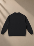 Unisex knitted round neck oversize sweatshirt in Black, laid flat on pale limestone, back view