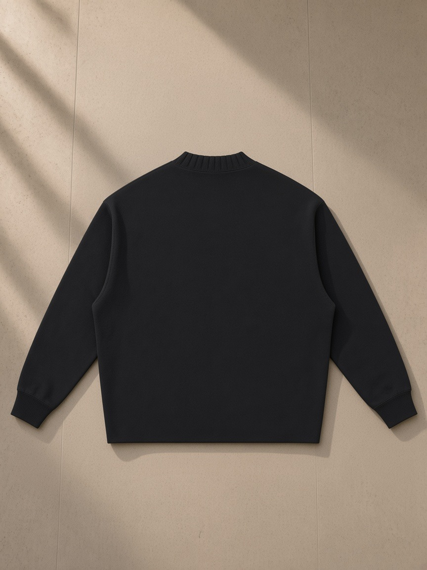 Unisex knitted round neck oversize sweatshirt in Black, laid flat on pale limestone, back view
