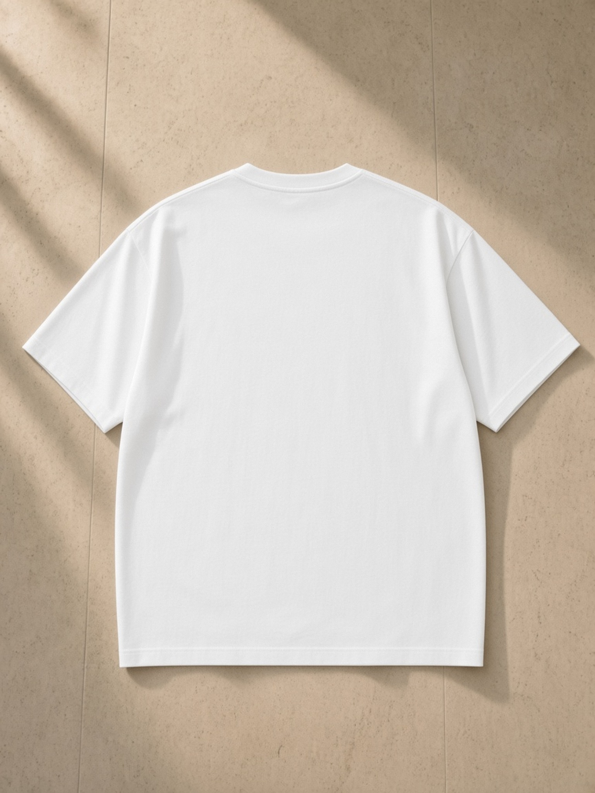 Streetwear Oversized Cotton T-Shirt in Lucent White, laid flat on pale limestone, back.