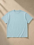 Lightweight oversized t-shirt in Haze Blue, laid flat on pale limestone