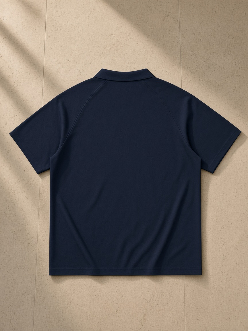 Classic Knit Polo in Navy Blue, laid flat on pale limestone, back view