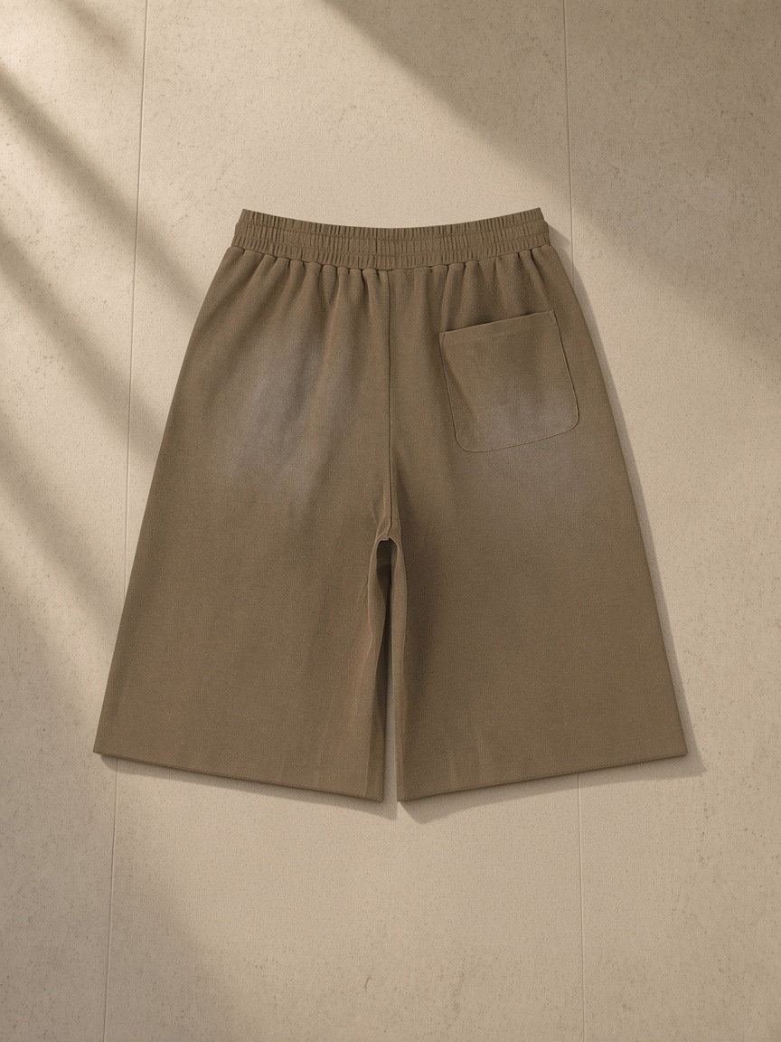 Unisex sunfade raw edge shorts in Coffee, laid flat on pale limestone, back view