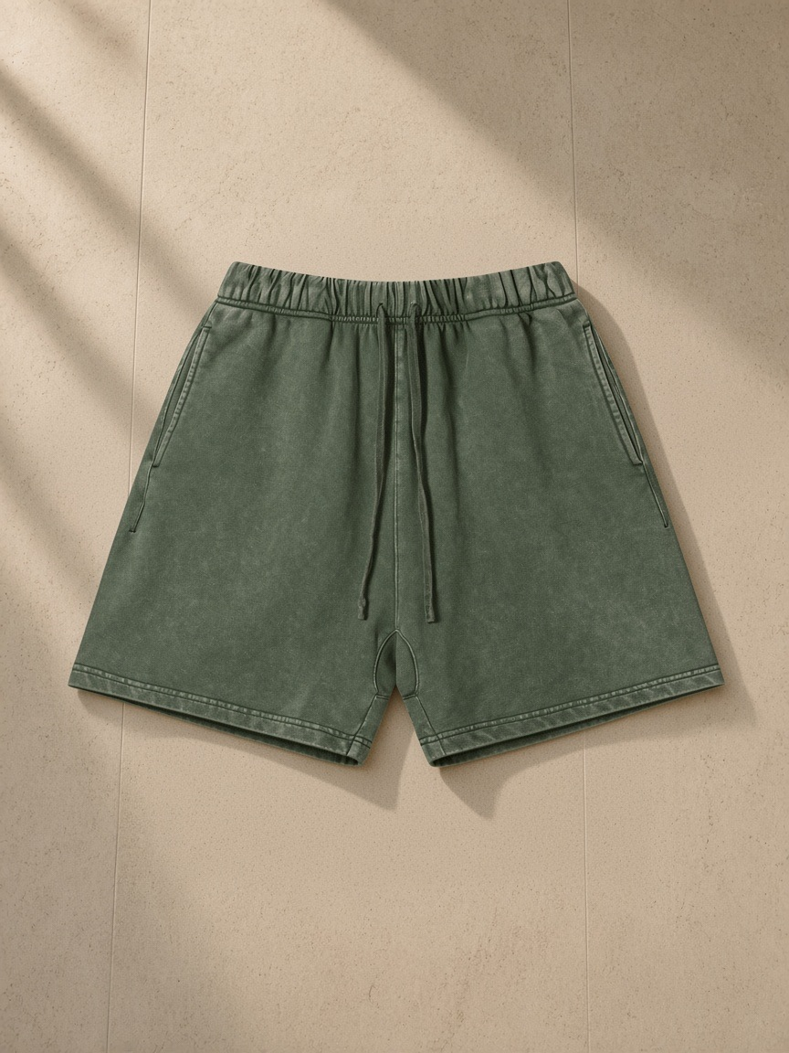 Vintage Wash Cotton Shorts in Army Green, laid flat on pale limestone