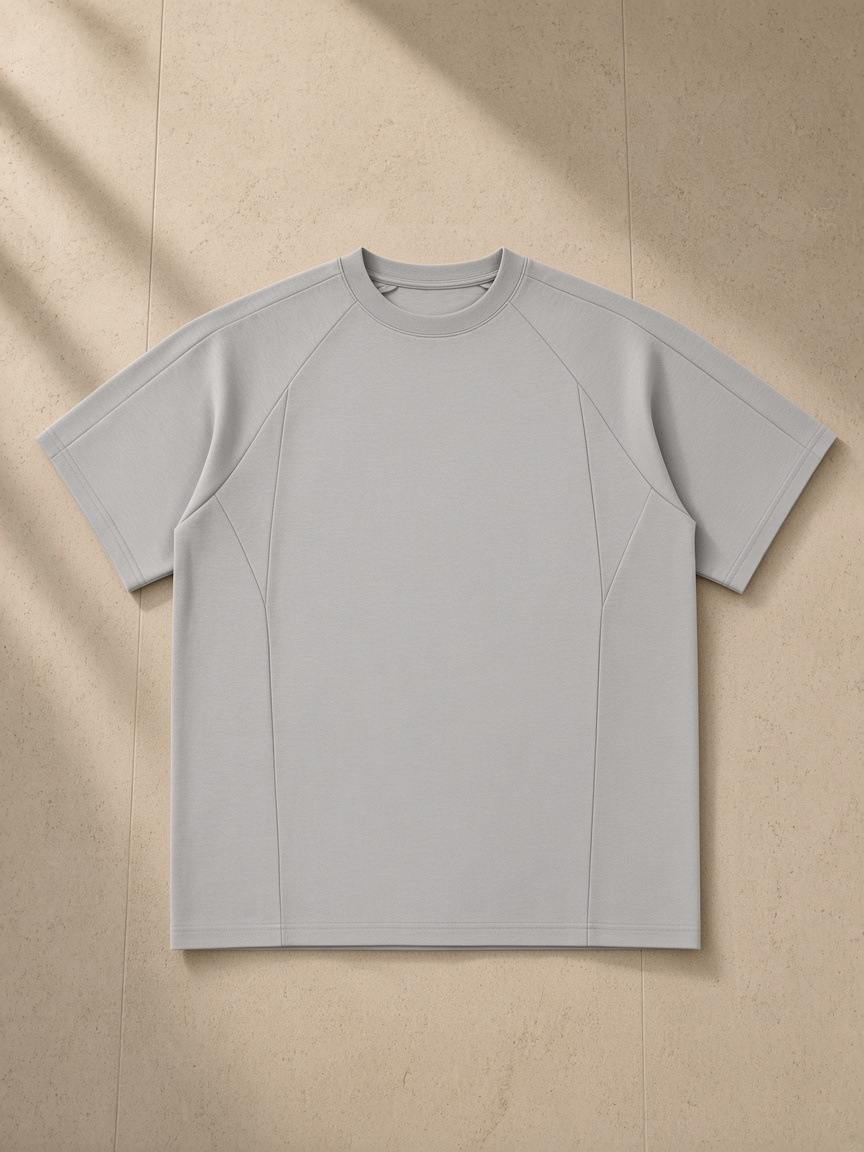 Oversized paneled raglan t-shirt in Light Gray, laid flat on pale limestone