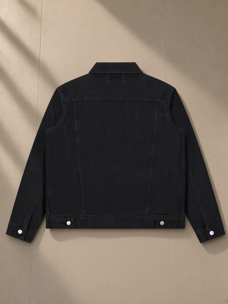 Vintage Wash Denim Jacket in Black, laid flat on pale limestone, back view