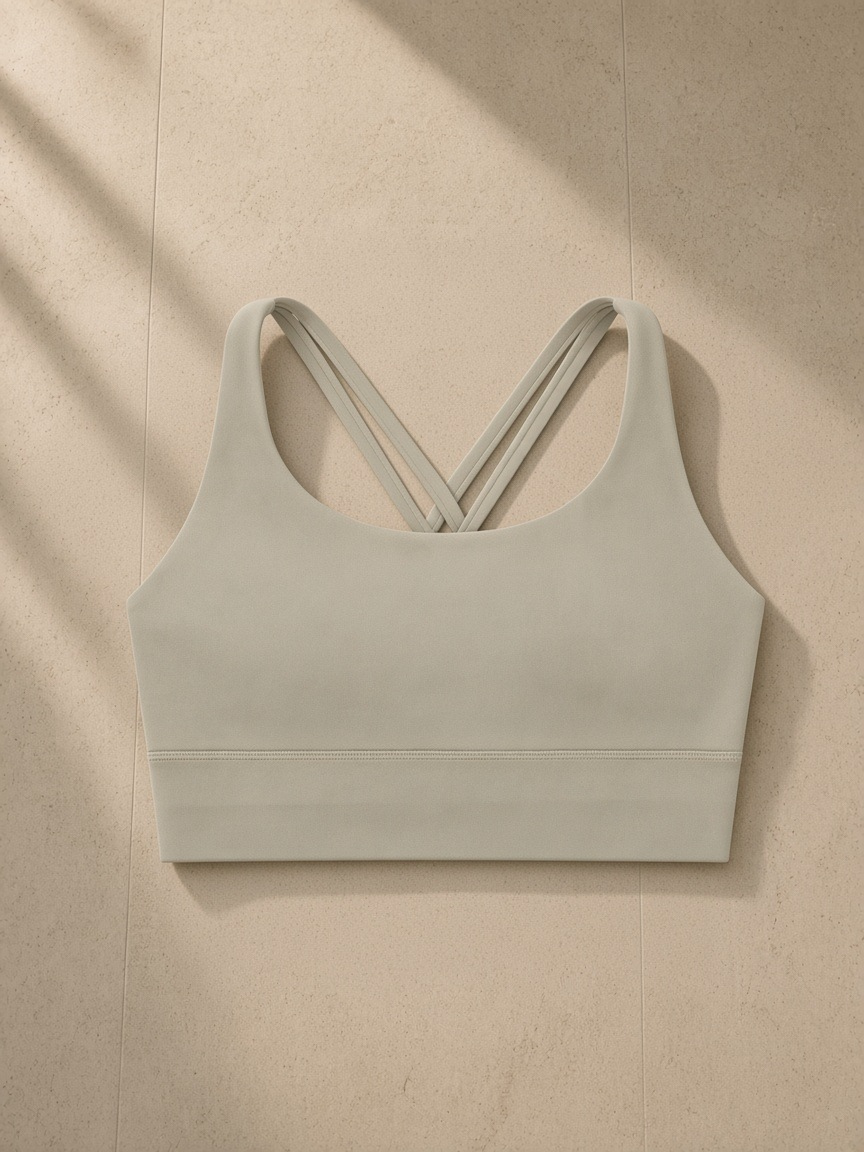 Strappy criss-cross sports bra in Light Gray, laid flat on pale limestone