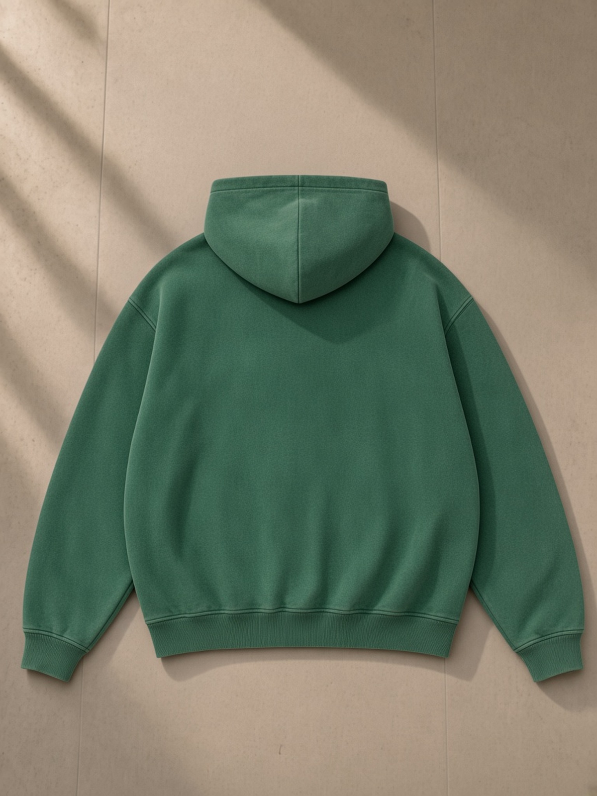 Snow Wash Fleece Oversize Hoodie in Dark Green, laid flat on pale limestone, back view